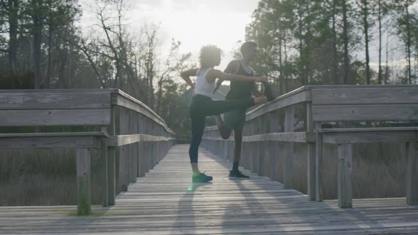 Man and woman on an outdoor deck stretching their bodies