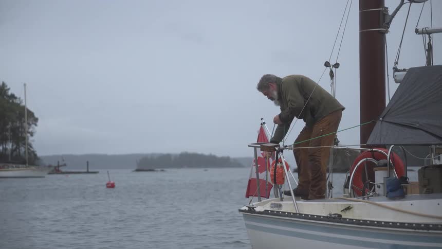 A man standing in a boat pulling a fishing net that is in the water