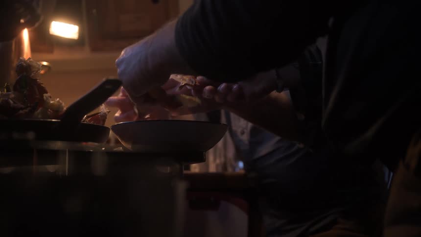 A couple people make food in a kitchen