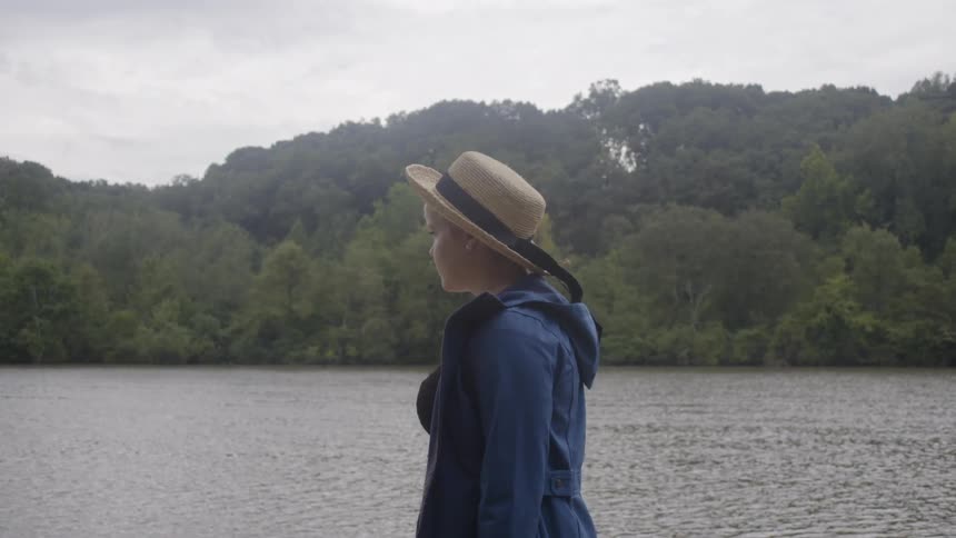 Woman stands next to a body of water looking out