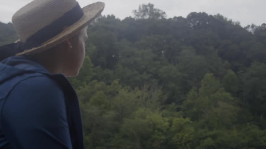 Woman looks out at hilly tree covered landscape