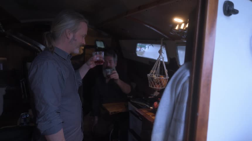 Two men toast and drink together on the boat