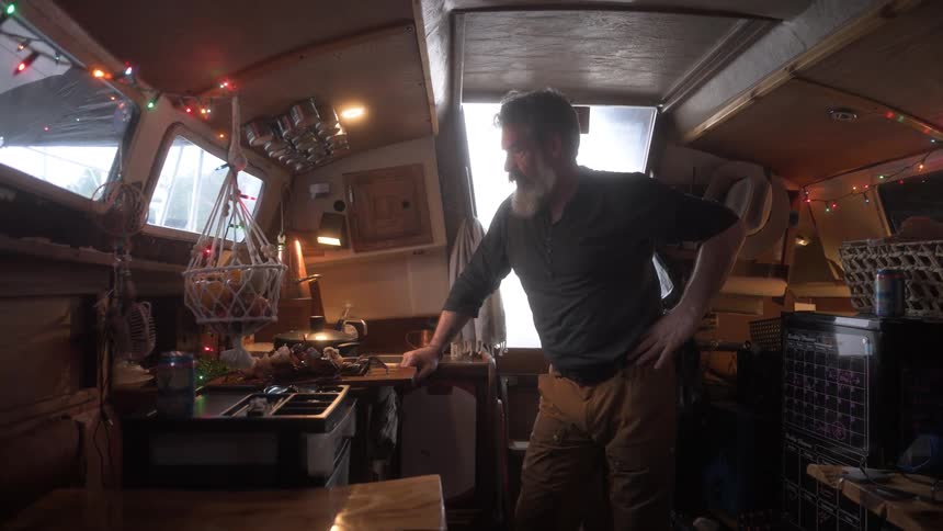 A man watches the pot that is cooking in the boat
