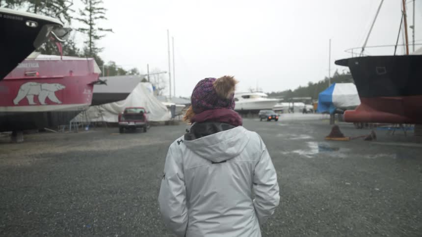 Woman in a cap walking in an environment with boats on a cloudy day