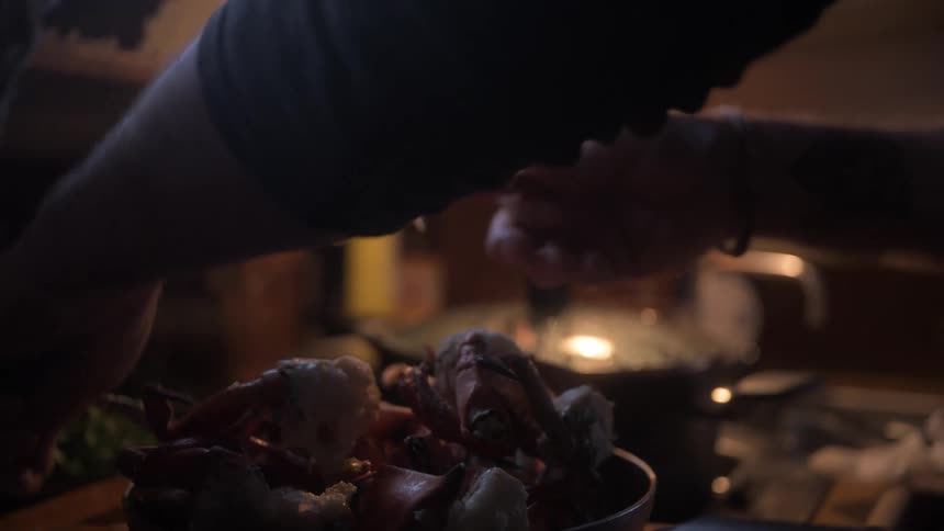 Pair of hands with pliers cutting crab into pieces while cooking