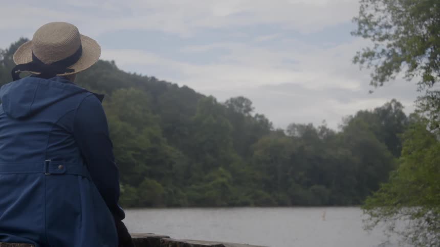 Woman looks out at the lake on a cloudy day