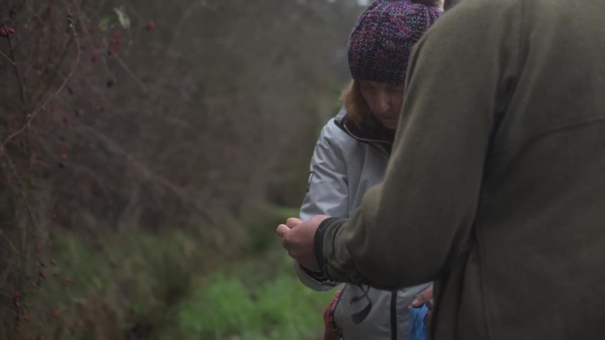 Man on a video call with another person next to a woman who is holding a green sprout