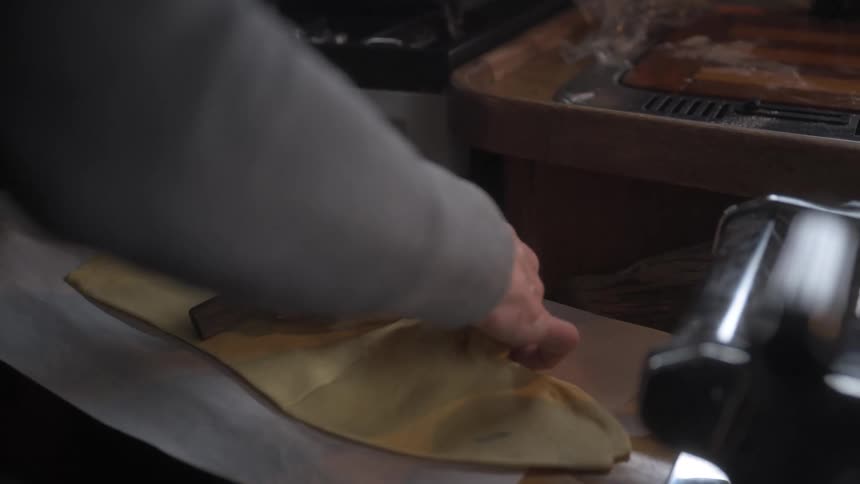 A person is cutting a sheet of dough with a knife