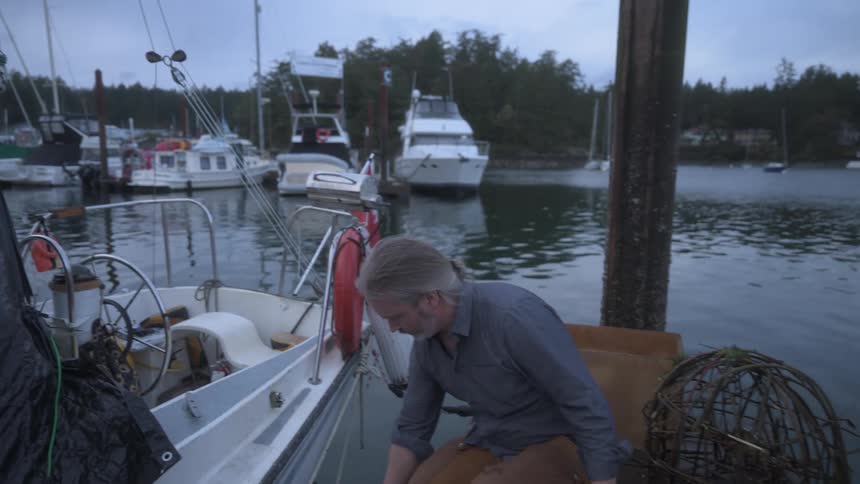 A man hands a live crab to another man as they get on a boat