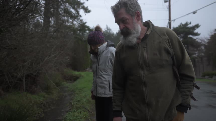 Man and a woman examine the roadside with sprouts