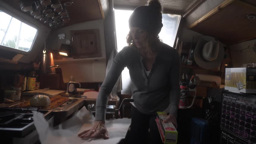 Woman in kitchen picking up a sheet of parchment paper