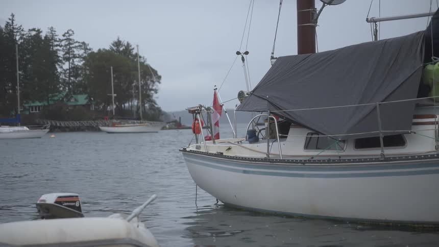 A man walks on his boat and pulls on a rope in the water