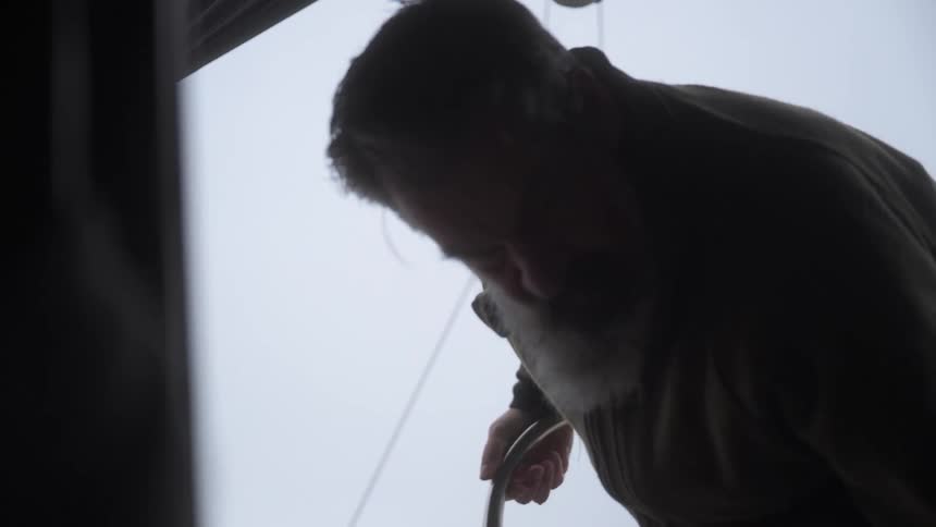 Man stomps just inside a tent and moves a small sheet of translucent material