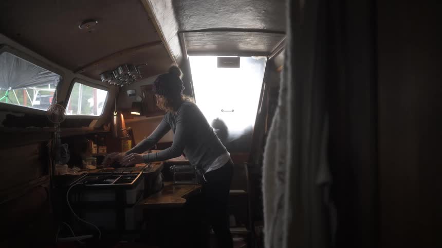 Woman in a kitchen inside a boat cooking