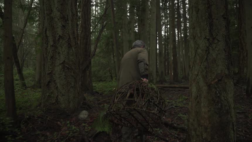Man with a fishing trap walking through a forest