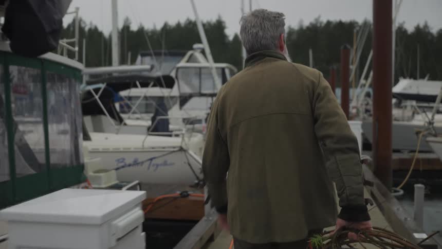 Man walking with a fishing trap along a marina dock