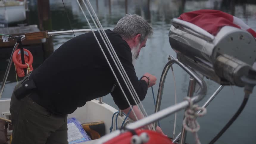 A man on a boat retrieves a fish trap from the lake that now has a fish in it