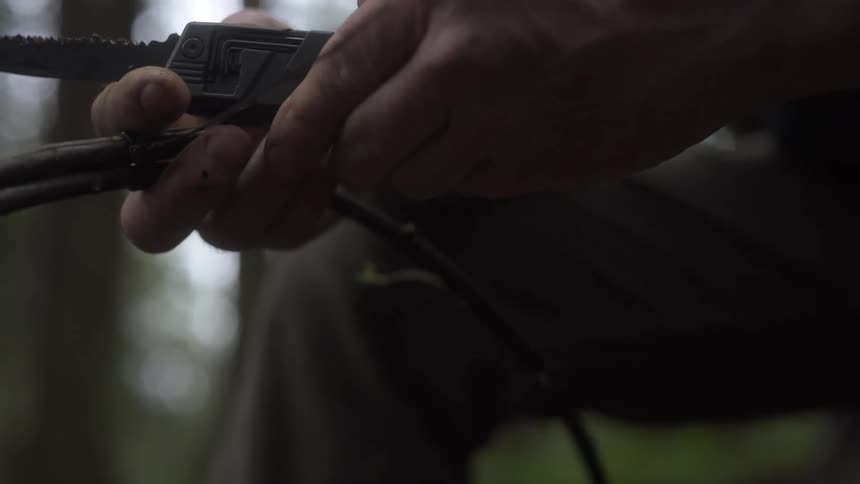 A man is stripping a branch with a knife