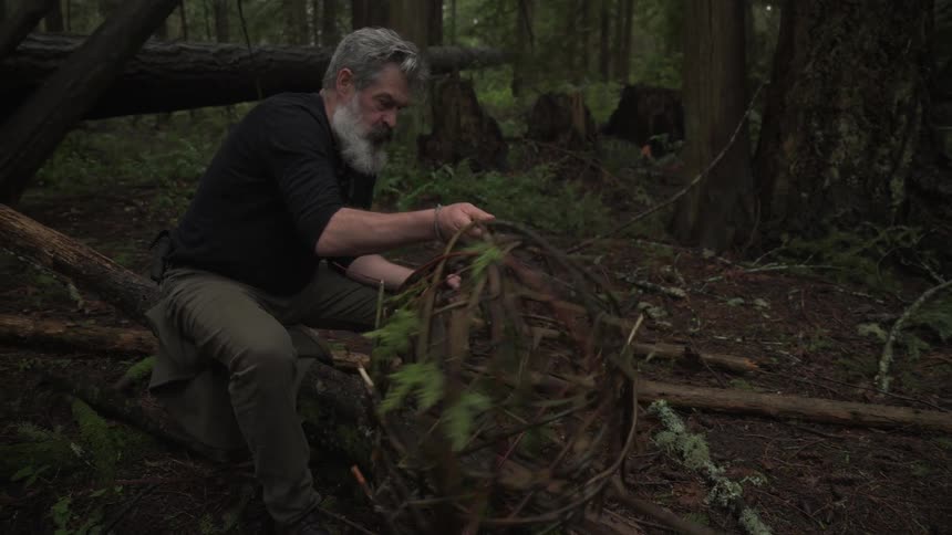 A footage of a man making a basket in the woods