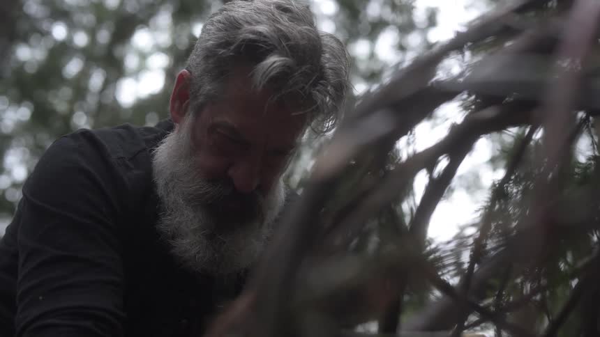 Man in a forest setting a fishing trap