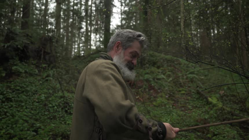 A man is measuring a branch in the woods