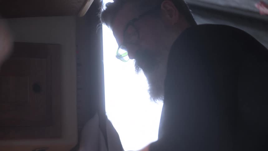 Man with white beard and glasses inside a cabin