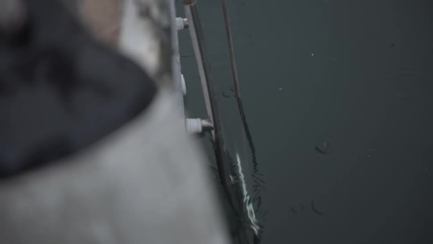A stick is dipping in the water off the side of a boat