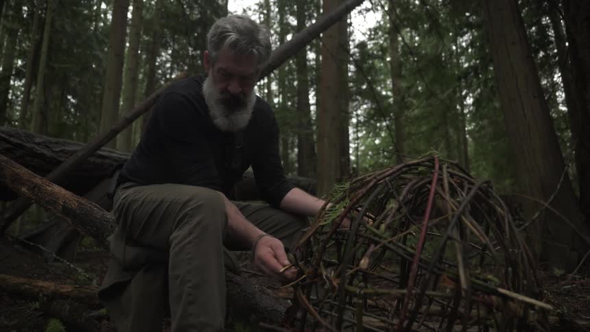 The hunter is building a trap out of sticks