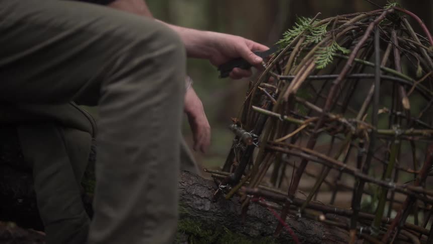 A man is building a trap with sticks