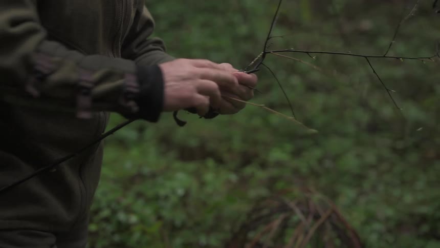 A footage of a man holding a knife and a stick branch