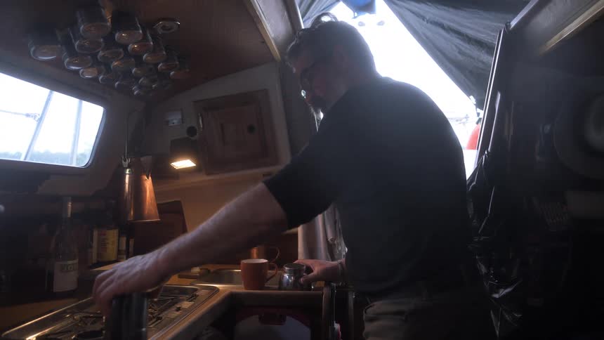 Man works at the stove in a portable kitchen covered by a tent during the daytime