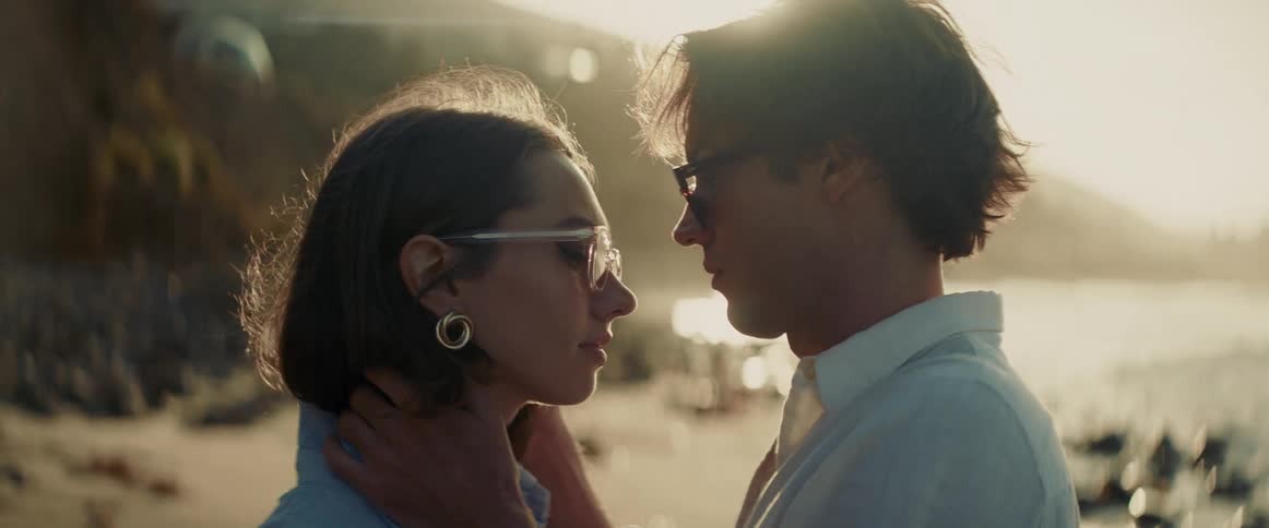 A man holds a womans head on the beach