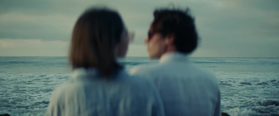 A footage of two people sitting by the beach side