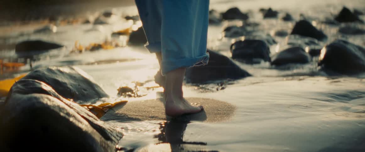 Legs of a woman walking on the sand on the beach