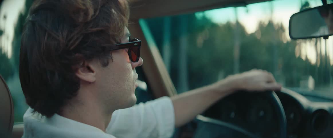 Man wearing sunglasses driving a convertible vehicle