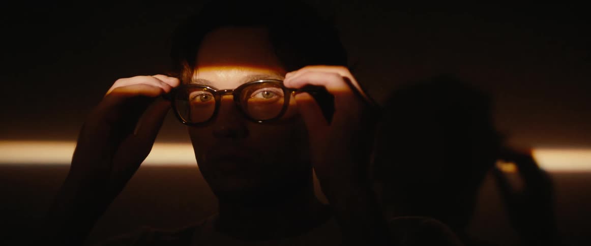 Silhouette of a mans face with a beam of light in his eyes putting on prescription glasses