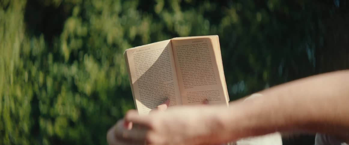 Pair of hands holding a book outdoors