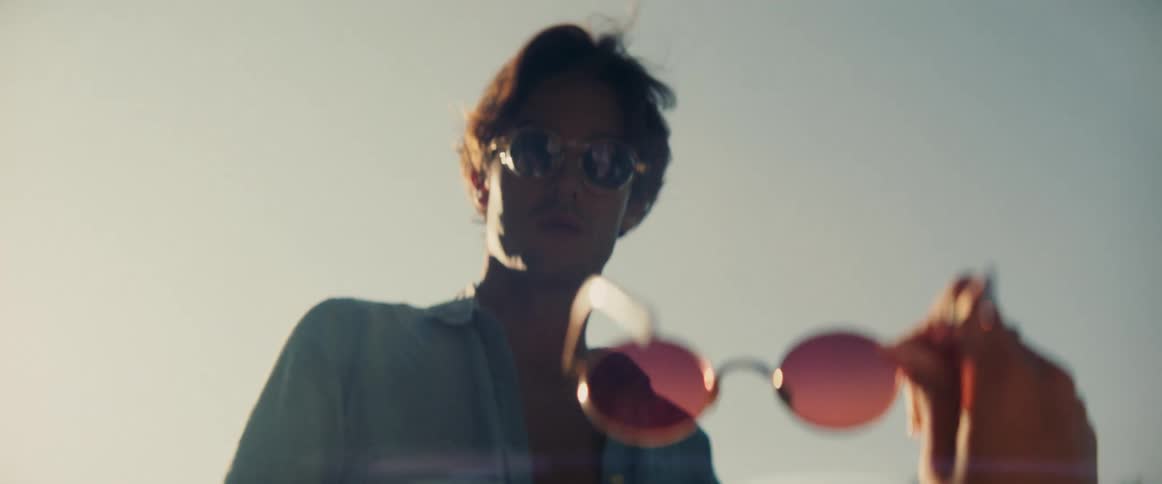 Man looking directly at a hand holding sunglasses