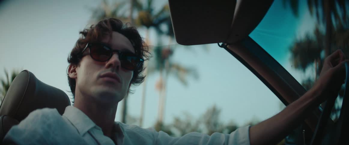 Man wearing sunglasses driving a convertible vehicle