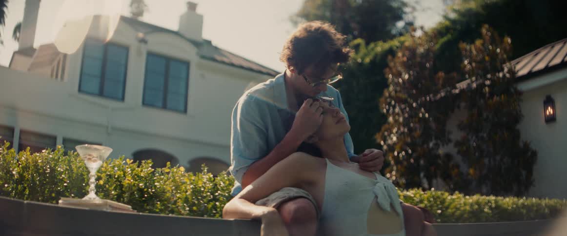 Woman and a man hugging in the pool with a house in the background