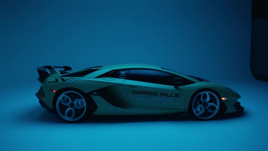 Blue light flickers on a green sports car with hidden hills advertised on the passenger door