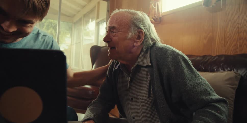 Two men talk and laugh at the laptop
