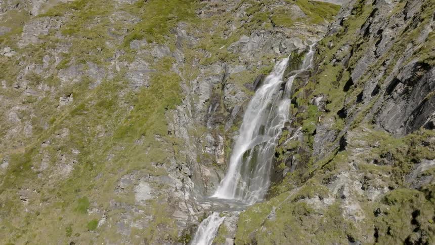 A river flows over the side of the mountain as a waterfall