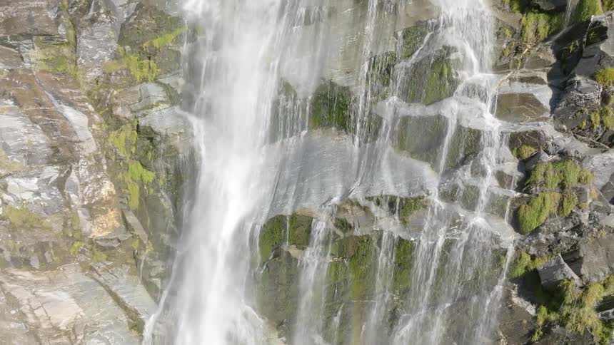 Water cascades down a rugged mosscovered rock face in a series of falls