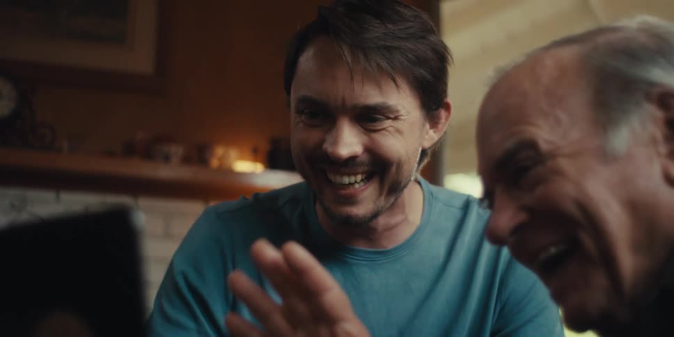 Elderly man and a young man interacting with a laptop screen with happy facial expression