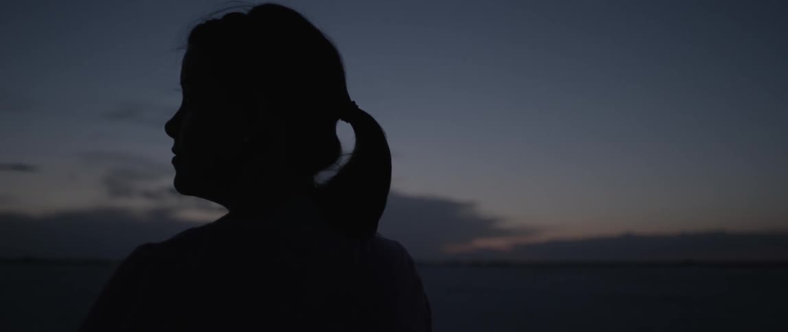 Silhouette of a woman standing outside at sunset