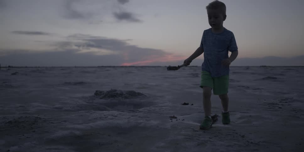 A boy plays in the dirt at sunset