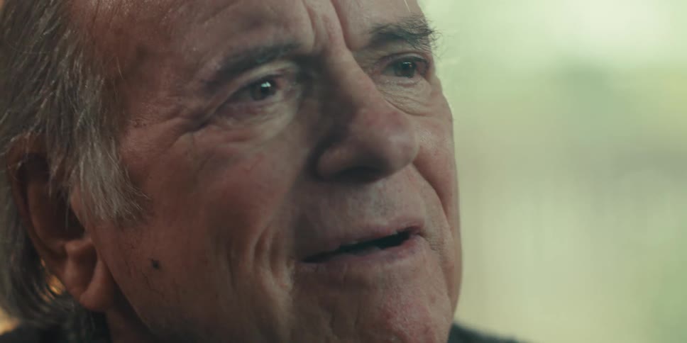 A close up of an elderly man sitting on a cozy home smiling