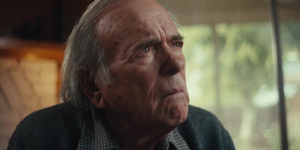 An elderly man appears worried while he speaks indoors