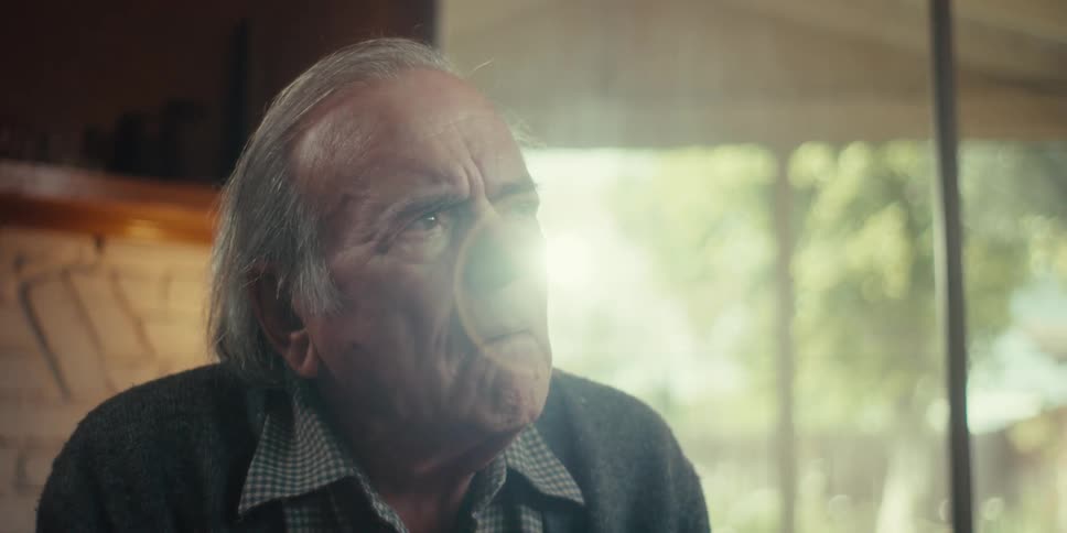 Elderly man in an indoor space talking to another young man